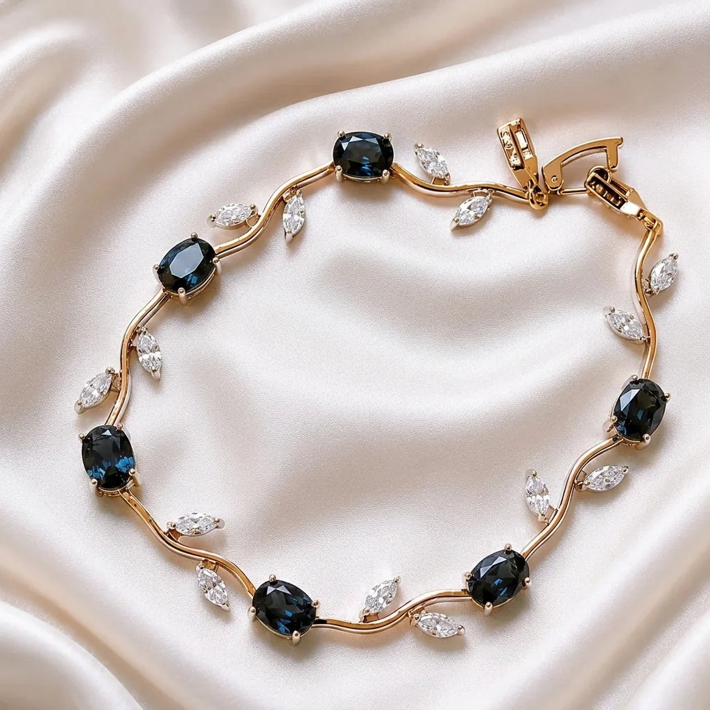 Gold bracelet with blue gemstones and clear stones on a white fabric background