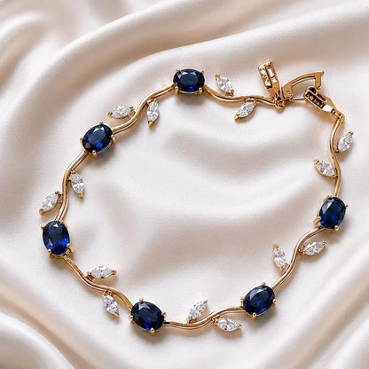 Gold bracelet with blue gemstones on a beige fabric background
