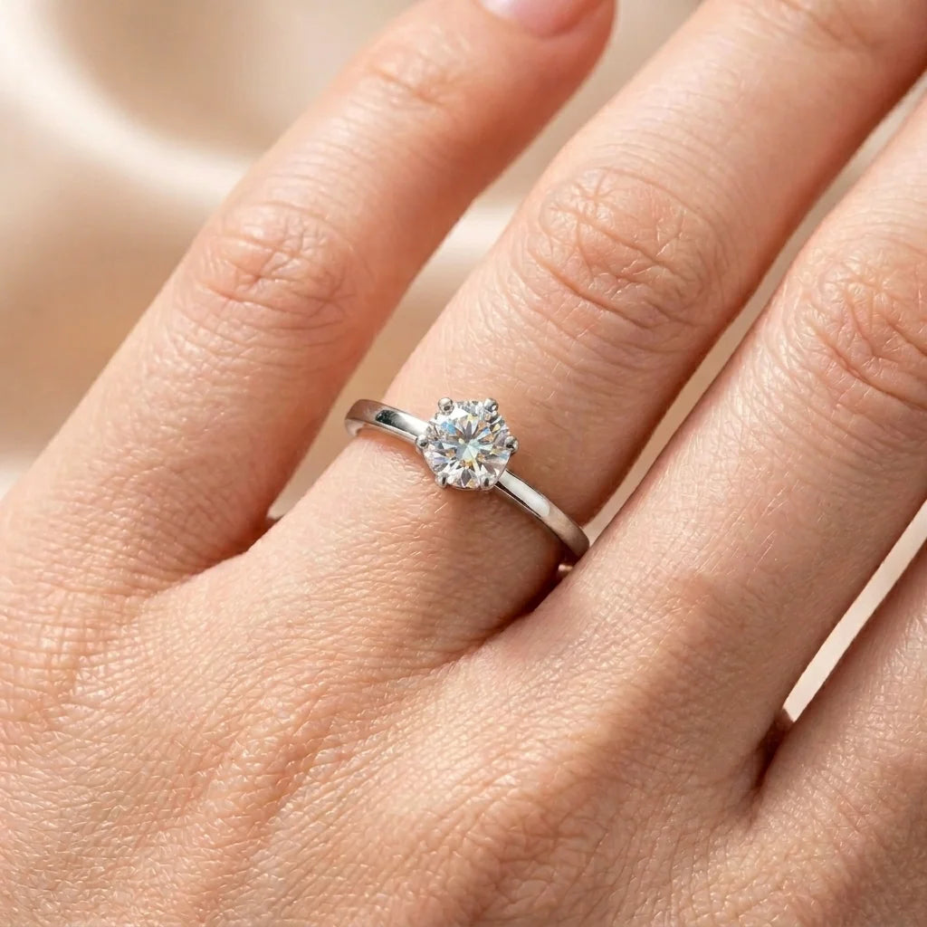 Gold ring with a diamond on a hand against a neutral background