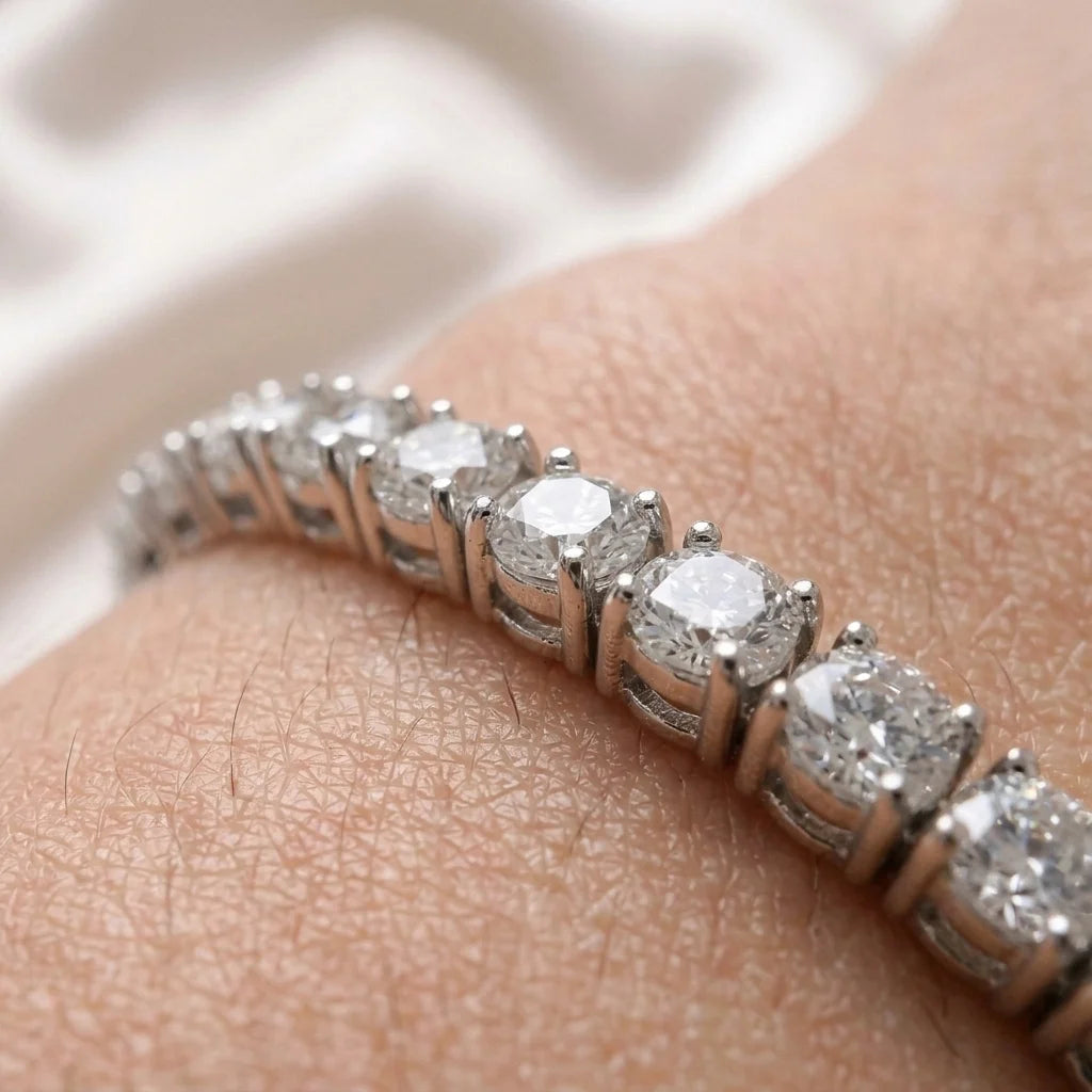 A close-up of a diamond tennis band ring worn on a person's finger, showing the silver-toned prongs and clear round-cut diamonds against skin.