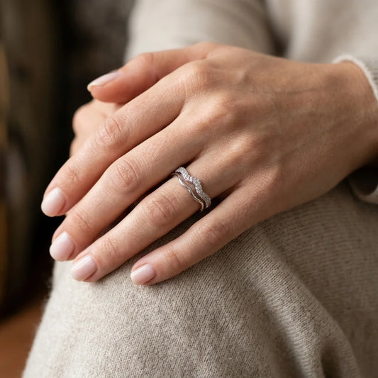 Hand wearing UPT sparkling pavé wave ring with a beige knit sweater