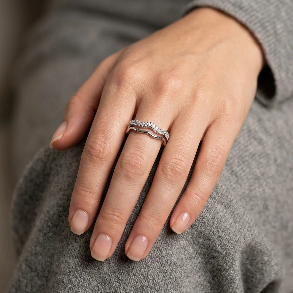 UPT silver-tone pavé crystal wave ring layered with a plain wave band on hand with grey knit