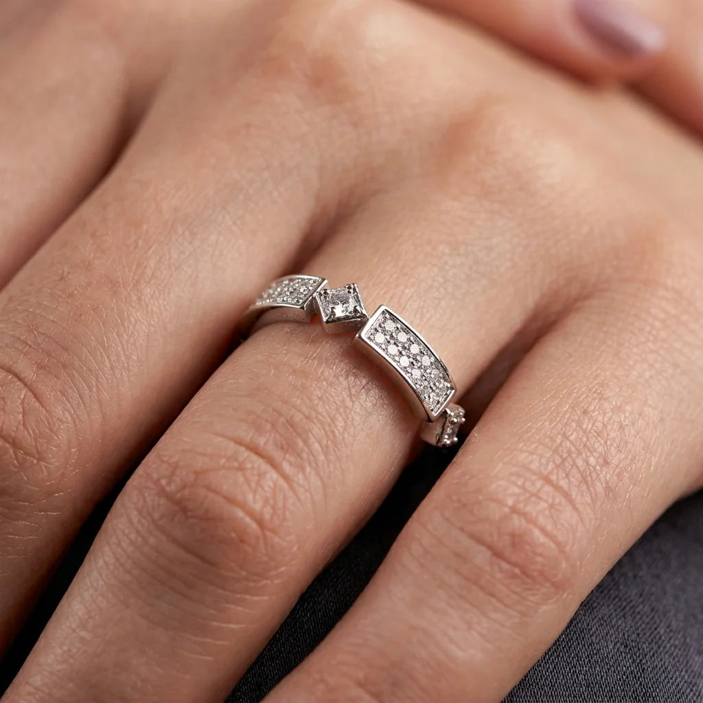 A close-up of a silver ring with pavé-set clear stones worn on a finger. Per the instructions, clear gemstones do not contribute to the color, so the product color is determined solely by the metal setting, which is silver.