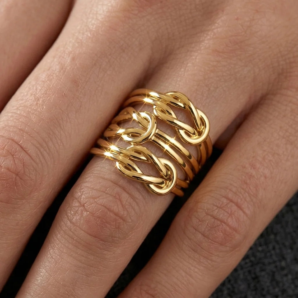 A close-up of a hand wearing a gold ring with multiple interlocking chain-like bands.