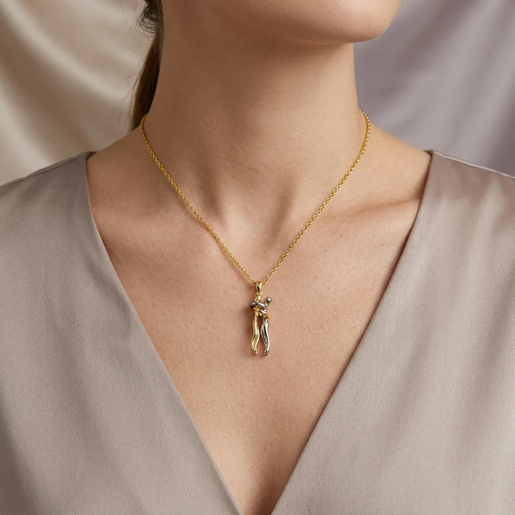 A close-up of a model wearing a delicate gold chain necklace with a small, polished gold pendant, styled with a taupe satin top.