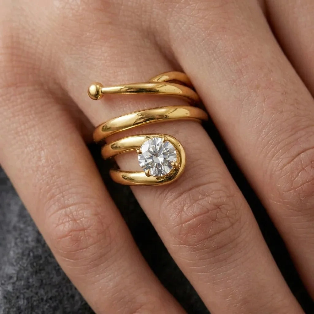 Close‑up of a gold spiral ring with a round diamond gemstone on a hand.