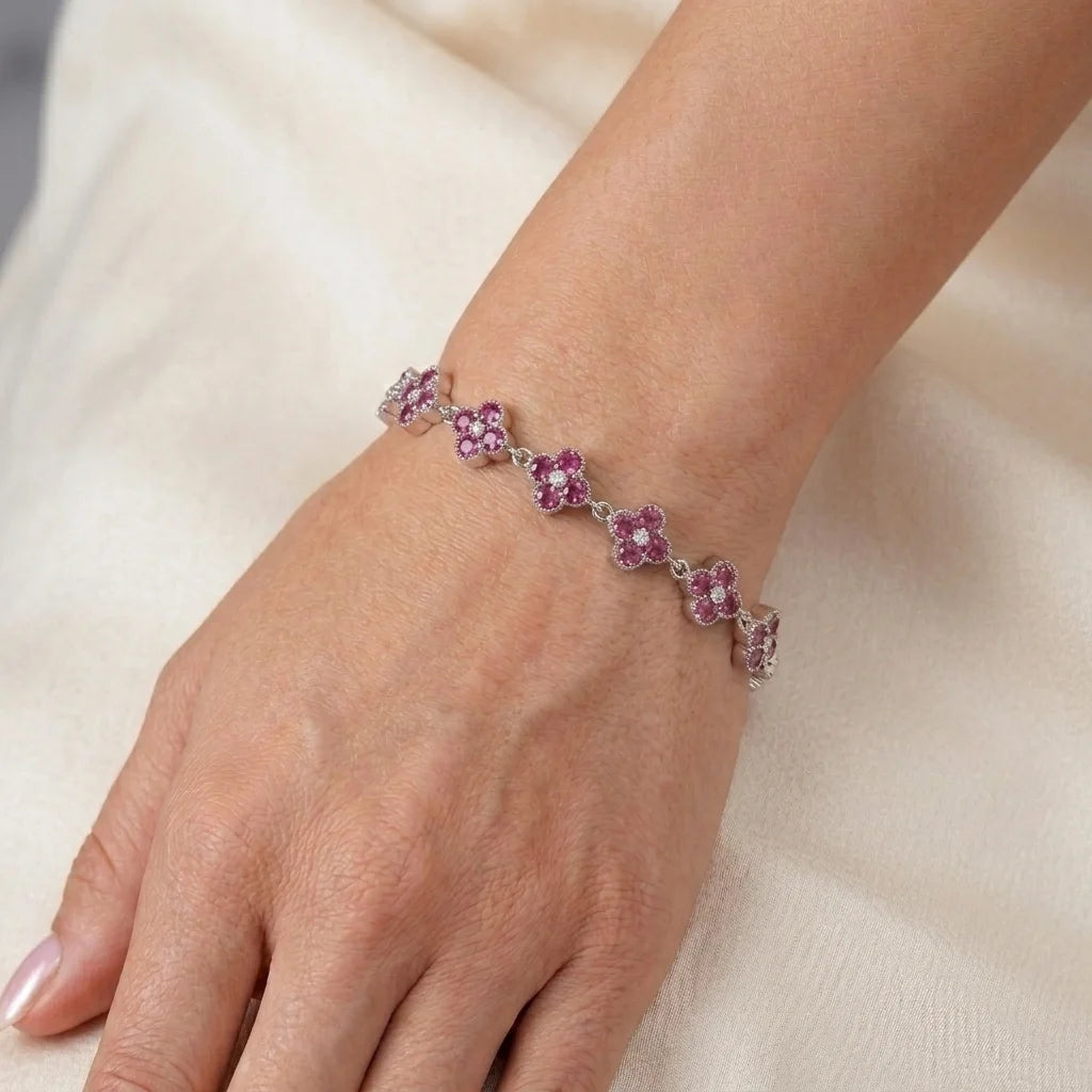 Silver pink sapphire-look clover bracelet with round pink stones and clear center gems, worn on wrist close-up