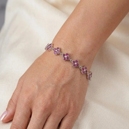 Silver pink sapphire-look clover bracelet with round pink stones and clear center gems, worn on wrist close-up