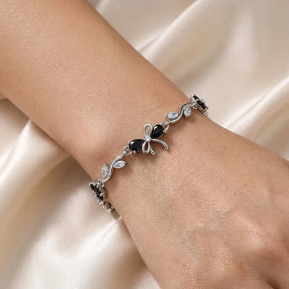 Black zircon on a sleek silver vine with a sculpted bow. After-dark sparkle, gift box included.