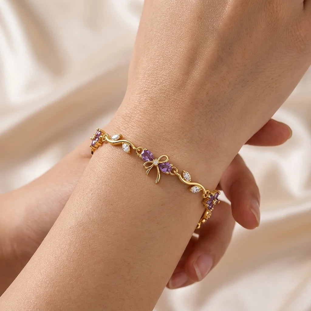Lavender zircon flowers wind along a gold-tone vine, crowned with a petite bow. Garden-party glam.