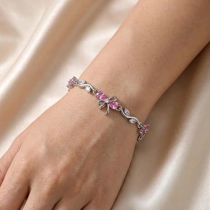 Blush-pink zircon flowers on a cool silver vine, tied with a delicate bow. Soft, sparkly, gift-ready.