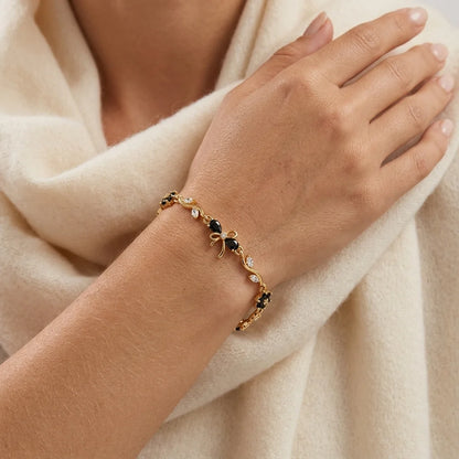 Midnight-black zircon blooms trail a gold-tone vine, finished with a dainty bow. Gift box included.
