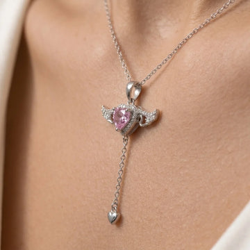 Close-up of the silver flying heart fidget pendant on a woman's neck, pink heart zircon with crystal angel wings and a mini heart drop chain