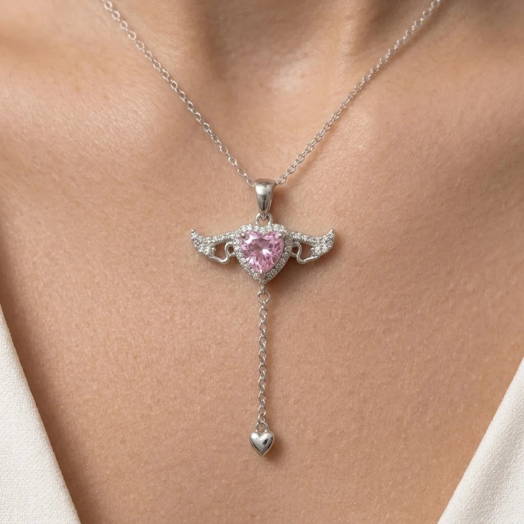 Close-up of the silver flying heart fidget pendant on a woman's neck, pink heart zircon with crystal angel wings and a mini heart drop chain