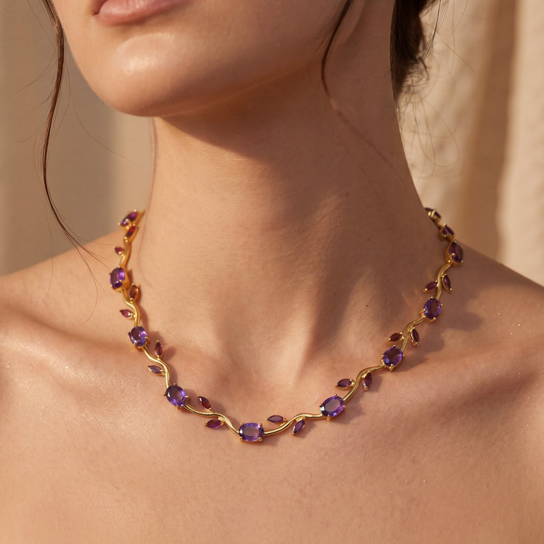 Necklace with purple stones worn by a person, against a neutral background