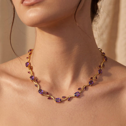 Necklace with purple stones worn by a person, against a neutral background