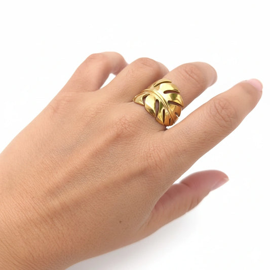 Gold leaf ring on a hand against a white background