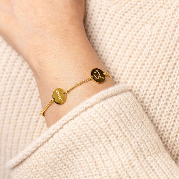 Gold bracelet with a unique design worn on a wrist against a beige sweater background