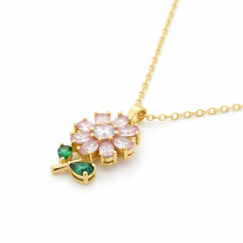 Gold necklace with a floral pendant featuring pink and green gemstones on a white background