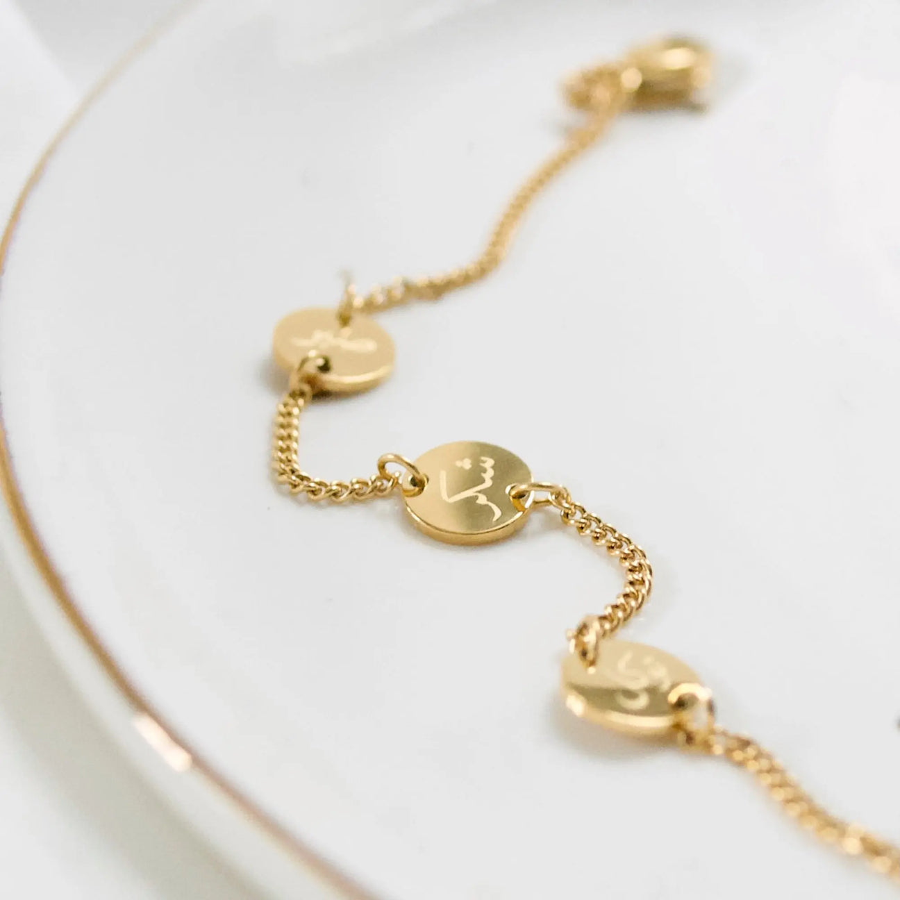 Gold bracelet with heart and round pendants on a white background