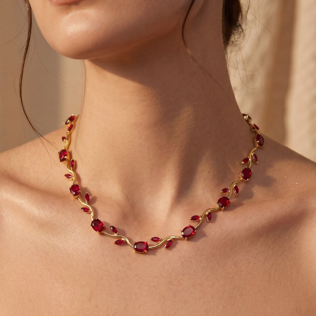 Woman wearing a red gemstone necklace against a neutral background