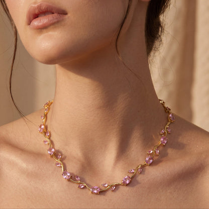 Woman wearing a delicate necklace with pink beads against a neutral background