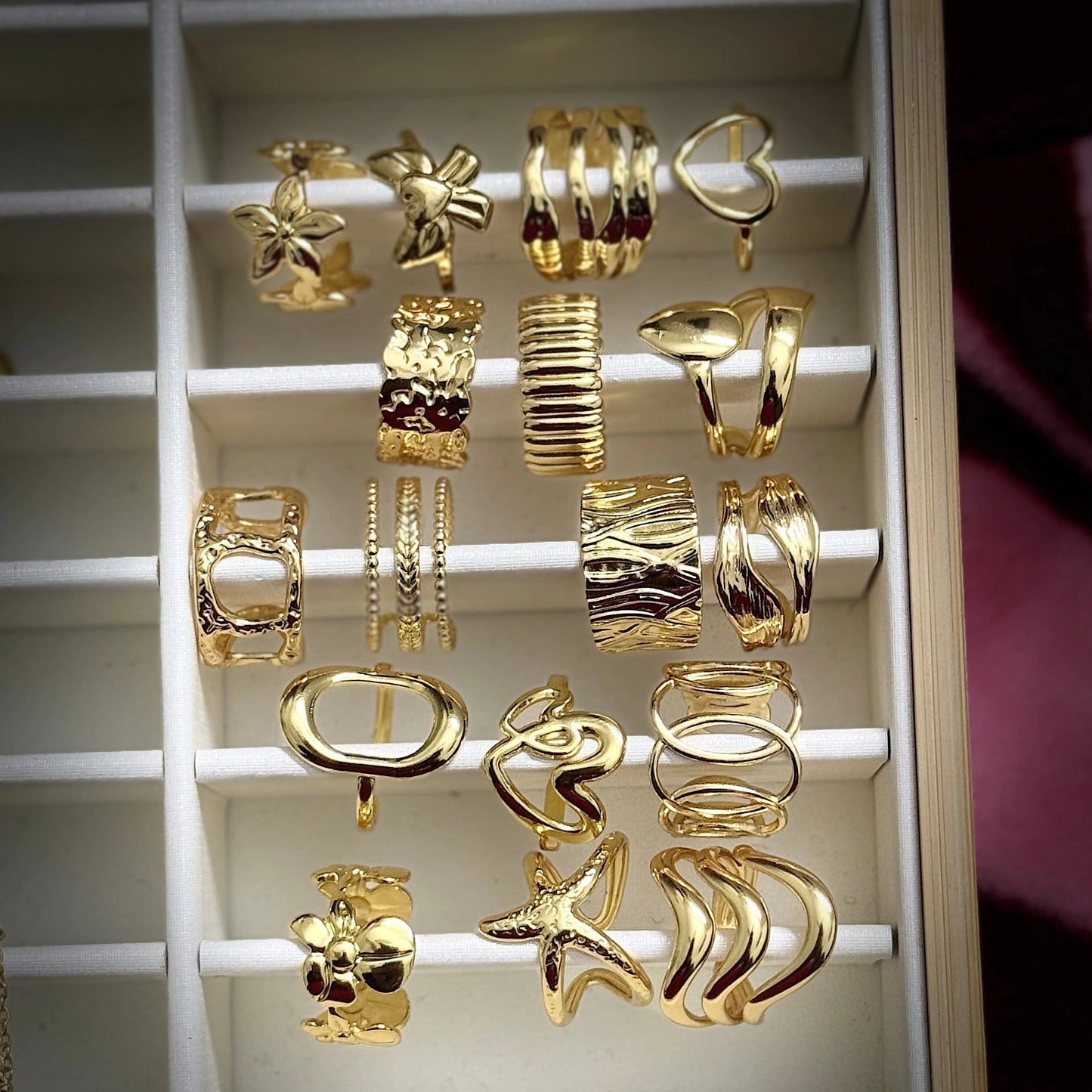 Collection of gold earrings displayed on a white rack.