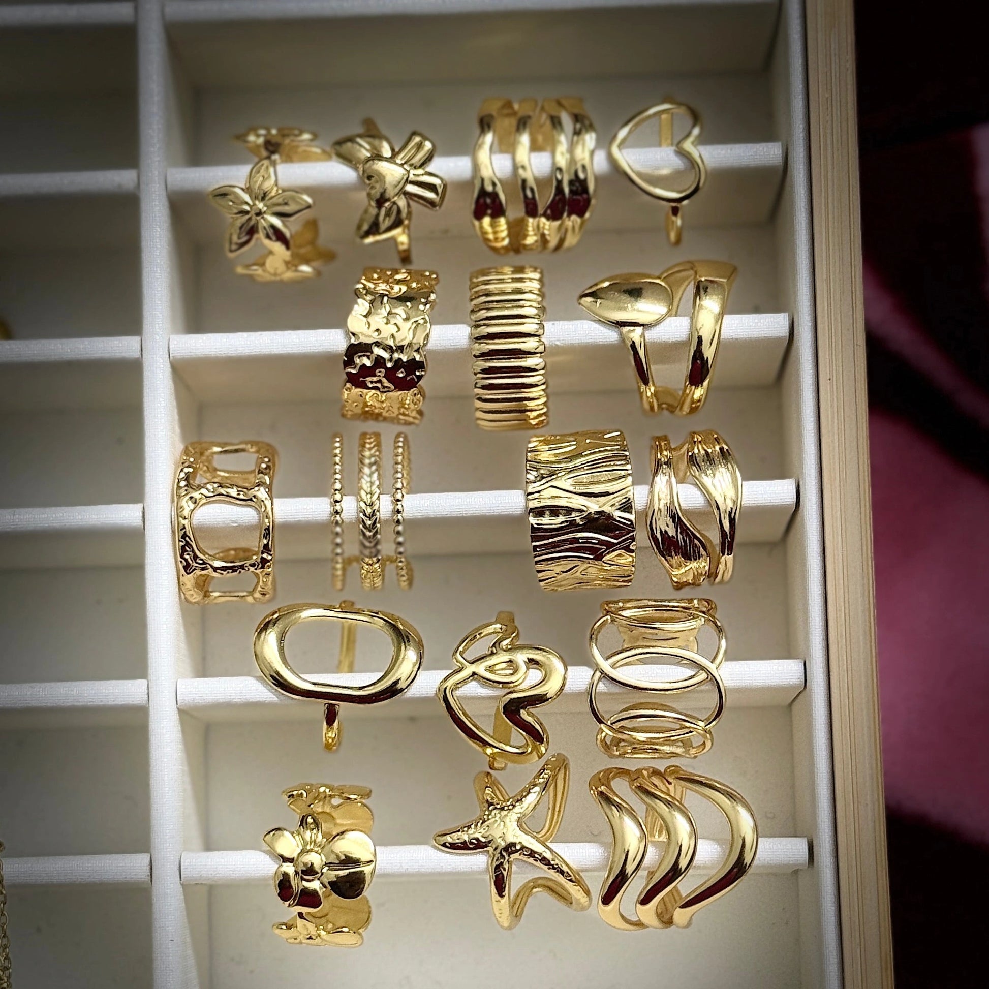 Collection of gold earrings displayed on a white rack.